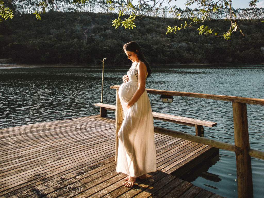 VIGEOVIT® Magnesium für Schwangerschaft. Schwangere Frau steht am Steg bei einem See.
