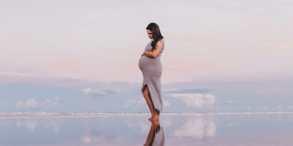 VIGEOVIT® Magnesium für Schwangerschaft. Schwangere Frau steht im Morgen im Wasser.